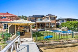 a house with a fence in front of a yard at Waterfront Luxury Pool-Spa-Jetty-Pool Table in Daleys Point
