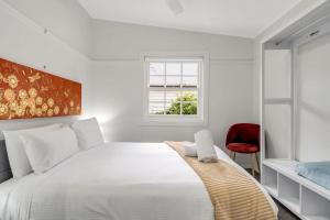 a bedroom with a large white bed with a red chair at Loch Lomond Home Mountain Retreat Katoomba in Katoomba