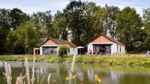 ein Haus neben einem Wasserkörper in der Unterkunft Bungalows Papillon Country Resort in Denekamp
