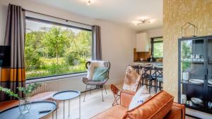 ein Wohnzimmer mit einem Tisch und Stühlen sowie einem großen Fenster in der Unterkunft Bungalows Papillon Country Resort in Denekamp