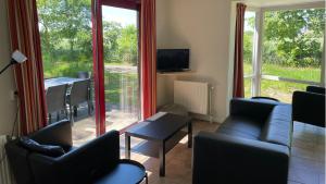ein Wohnzimmer mit einem Sofa, Stühlen und einem Fenster in der Unterkunft Bungalows Papillon Country Resort in Denekamp