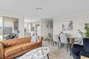 a living room with a couch and a table at Wine Country Cottage Stylish Family Getaway in Cessnock