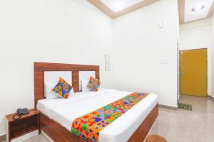 una camera bianca con un grande letto con cuscini colorati di FabHotel Shree Venkatesh Nileyam a Ayodhya