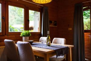 a dining room table with a bottle of wine and chairs at Huisdiervriendelijk houten huisje in het groen in Epe