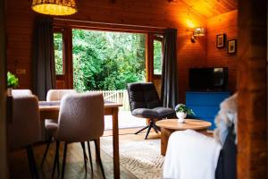 a living room with a dining room table and chairs at Huisdiervriendelijk houten huisje in het groen in Epe