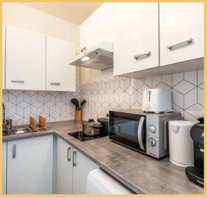 a kitchen with white cabinets and a microwave at Le Salève I Studio I Etrembières in Monnetier-Mornex