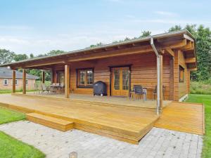 a log cabin with a large wooden deck at 5 star holiday home in Hadsund in Hadsund