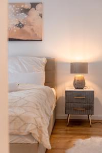 a bedroom with a bed and a lamp on a night stand at Traumhaftes Apartment -Balkon -Hängesessel -WiFi in Viersen +17 photos