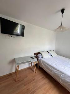 a bedroom with a bed and a table and a tv at CHAMBRE de LUXE in Nandy