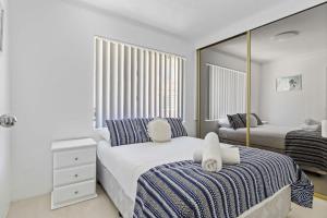Un dormitorio blanco con dos camas y un espejo. en Parklea Sun Seabreeze The Entrance Sleeps 5, en The Entrance