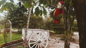 a wooden parrot hanging from a tree next to a cart at Cabañas Carayá in Paso de la Patria