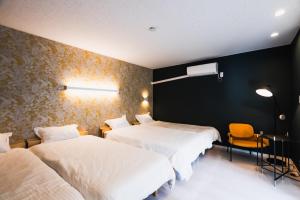 a bedroom with two beds and a yellow chair at Villa Myoden in Ichikawa