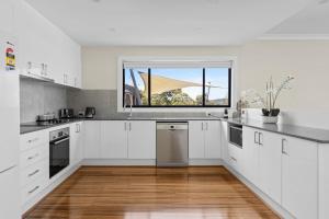 una cucina con armadietti bianchi e una finestra di Lakeview Oasis on The Esplanade a Warners Bay