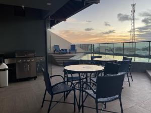 a restaurant with tables and chairs on a balcony at Apto a 150m da praia, Rooftop com piscina & sauna em Porto de Galinhas in Porto De Galinhas