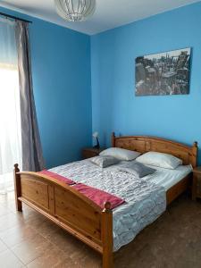 a bedroom with a wooden bed in a blue wall at Садиба "Мапа" in Berehove