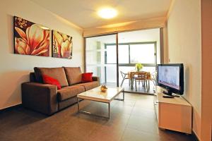 a living room with a couch and a tv and a table at Aparthotel Diamant Blue in Playas de Orihuela