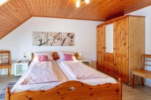 a bedroom with a large wooden bed with pink pillows at Haus Am Bühl in Schönau im Schwarzwald
