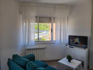 a living room with a blue couch and a window at Apartamentos Turísticos Buenavista in La Robla