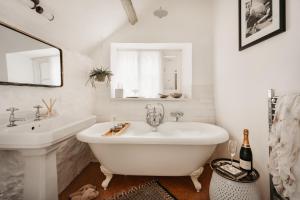 a white bathroom with a tub and a sink at Weeke Brook - Quintessential thatched luxury Devon cottage in Chagford +27 photos
