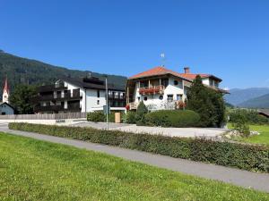 une grande maison blanche sur le côté d'une route dans l'établissement Astor Apartments, à Valdaora