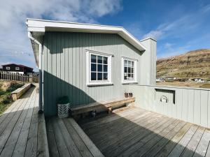 ein Haus mit einer Bank auf einem Holzdeck in der Unterkunft Cosy Two-bedroom Cottage In Lovely Surroundings in Froðba