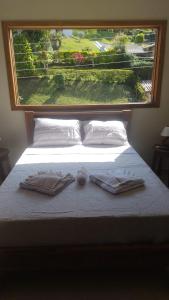 un letto con due asciugamani sopra con una grande finestra di Pousada Vida Cunha a Cunha