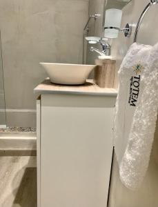 a white bathroom with a sink and a bowl on a counter at Hotel TOTEM Boutique in Termas de Río Hondo