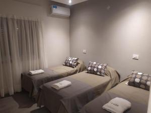 a room with three beds with towels on them at Hotel TOTEM Boutique in Termas de Río Hondo