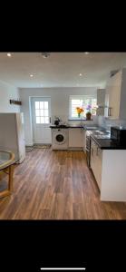 a kitchen with white appliances and a wooden floor at Seashells in Padstow