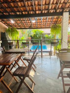 a patio with wooden tables and chairs and a pool at Casa Kuki's in Pipa