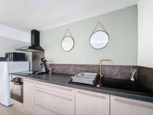 a kitchen with a sink and two mirrors on the wall at Évasion Verte - Jardin & Confort in Dunkerque +6 photos
