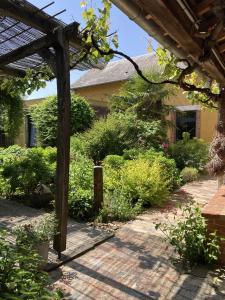 a garden with a wooden pergola and some bushes at Le 16 maison d'hôtes en Berry in Henrichemont