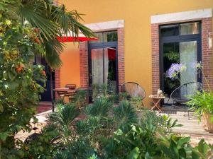 a patio with chairs and plants in front of a building at Le 16 maison d'hôtes en Berry in Henrichemont