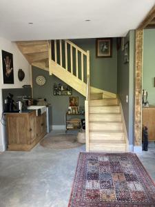 a living room with a wooden staircase and a kitchen at Le 16 maison d'hôtes en Berry in Henrichemont