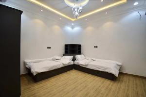 two beds in a room with white walls and a chandelier at شاليهات درة المئة in Ḩajlah +55 photos