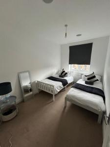 a white room with two beds and a mirror at Ipswich town centre two bed apartment in Ipswich