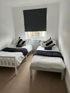 two twin beds in a room with a window at Ipswich town centre two bed apartment in Ipswich +13 photos