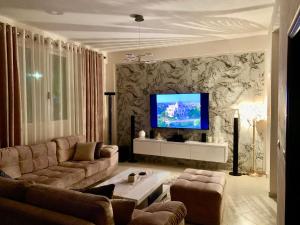 a living room with a couch and a tv on a wall at Villa Leandro in Fier