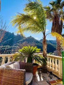 a balcony with chairs and palm trees and a mountain at Maison conviviale à Fréjus avec piscine à débordement in Fréjus