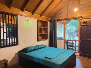 a bedroom with a bed in a room with a window at Sand Dune Beach Hotel & Surf Camp in Arugam Bay