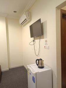 a room with a tv on the wall and a refrigerator at فندق مناير الاصول in Al Khansāk +14 photos