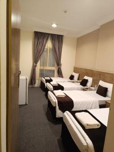 a row of four beds in a hotel room at فندق مناير الاصول in Al Khansāk