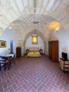 a bedroom with a bed in a room with a stone wall at Masseria Montanari in Carpignano Salentino
