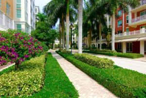 a walkway in front of a building with flowers and palm trees at Luxurious, family-friendly 3BR condo on the water in Lantana