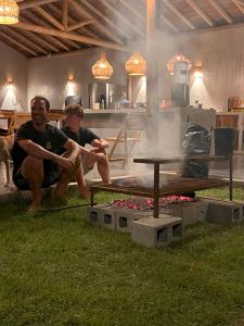 two men sitting in front of a fire pit at 4 Coqueiros GURIU in Guriú