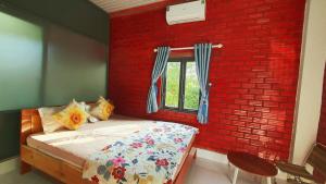 a bedroom with a red brick wall and a bed at Cat Tien Backpackers Hostel in Cat Tien