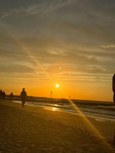 grupa ludzi spacerujących po plaży o zachodzie słońca w obiekcie Apartament Kasprowicza 12A w Kołobrzegu