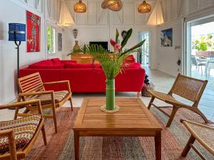 un salon avec un canapé rouge et une table dans l'établissement Villa Les Arbres Voyageurs sur les hauts de Saint François, à Saint-François
