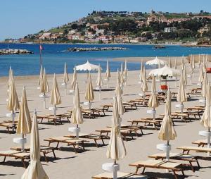 Ein Haufen Sonnenschirme und Stühle am Strand in der Unterkunft Casa Peonia in Taggia