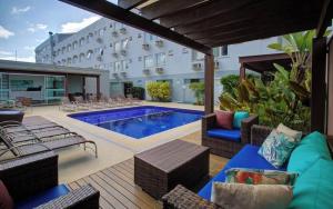 a patio with a pool and chairs and a building at GoldMen Business Joinville in Joinville